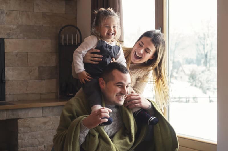 Young family on winter vacation, looking through window